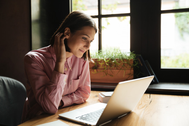 vue-laterale-femme-brune-souriante-assise-pres-table_171337-9604
